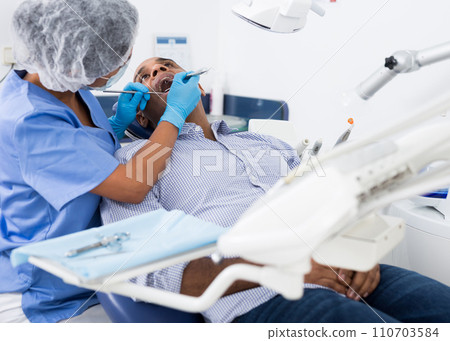 Man sitting with open mouth during dental checkup at dentist Man sitting with open mouth during dental checkup at dentist 110703584