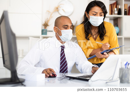 Office employees in medical masks working with papers and laptop 110703655