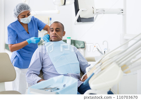 Woman dentist preparing man for dental examination in clinic Woman dentist preparing man for dental examination in clinic 110703670