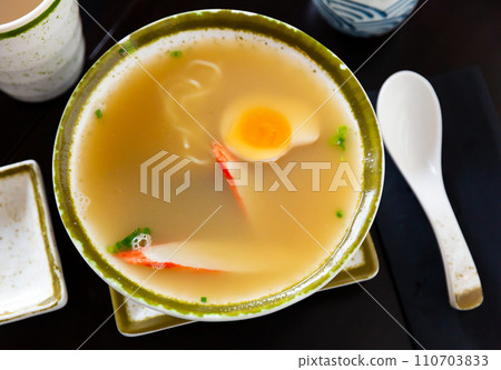 Bowl of asian soup ramen with wheat noodles, mushrooms and egg on table. Japanese cuisine 110703833
