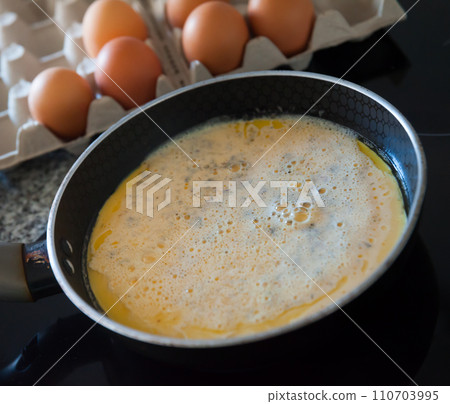 Cooking an omelette in frying pan for breakfast Cooking an omelette in frying pan for breakfast 110703995