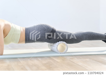 A woman using a foam roller to loosen her thighs 110704024