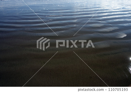在海灘上觀看潮起潮落。當沙子暴露在海浪中時，您會被沙子所形成的神秘圖案所吸引。 110705193