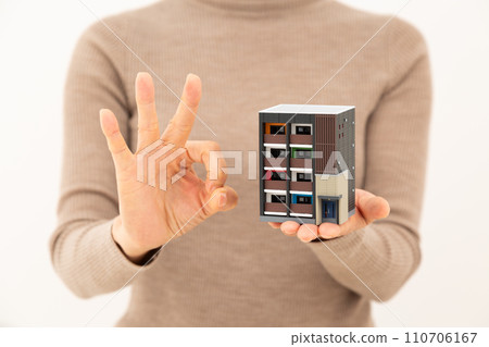 一名中年婦女拿著公寓大樓的模型，畫了一個圓圈標誌 110706167