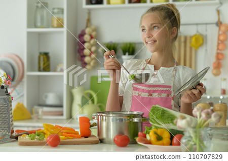 Portrait of a beautiful girl preparing a salad in the kitchen 110707829
