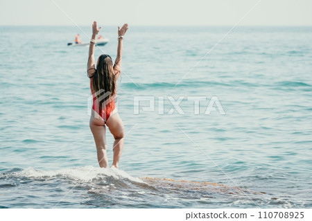 Woman sea yoga. Back view of free calm happy satisfied woman with long hair standing on top rock with yoga position against of sky by the sea. Healthy lifestyle outdoors in nature, fitness concept 110708925
