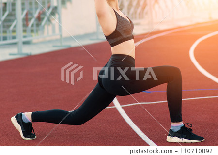 A female in a medical mask alone in an empty stadium with red seats. 110710092