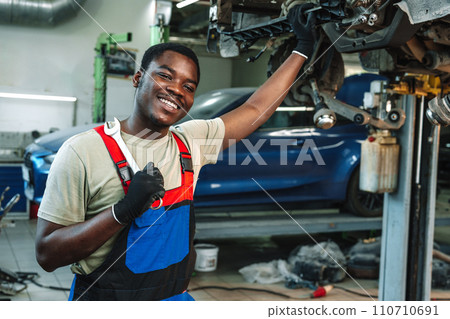 Portrait of young african man car service worker wearing uniform standing in garage 110710691
