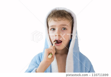 small child, boy in a blue terry robe with a toothbrush on white. A child brushes his teeth. Healthcare and dental care small child, boy in a blue terry robe with a toothbrush on white. A child brushes his teeth. Healthcare and dental care 110711899