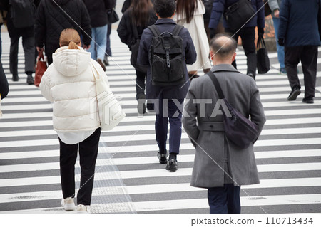 People crossing a crosswalk at an intersection in a winter city 110713434