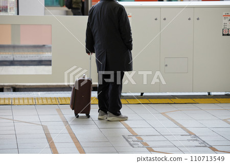 A senior man waiting for the train with a suitcase on the platform of Nagoya Station in winter 110713549