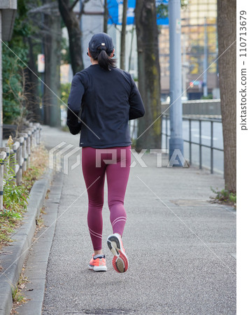 A female runner running on the path of the Imperial Palace Garden in Tokyo in winter 110713679