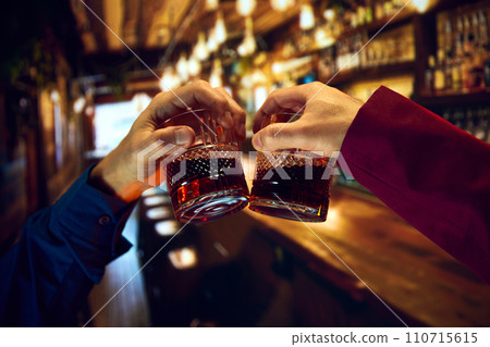 Male hands, businessmen clinking whiskey glasses, meeting at pub, restaurant. Friends meeting 110715615