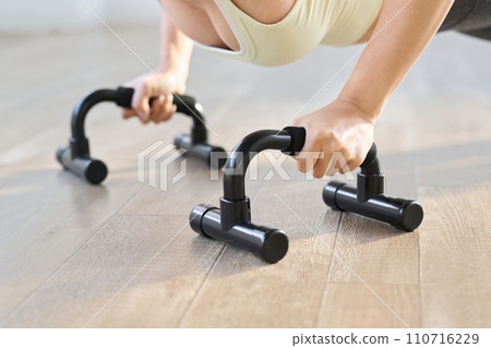 Woman doing push-ups using a push-up bar 110716229