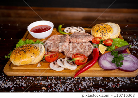 Process of cooking burgers. Cropeed view of chef hands in black gloves with prepared cheeseburger, variety of fillings and ingridients on wooden desk. Catering and Good Quality Fastfood concept 110716308