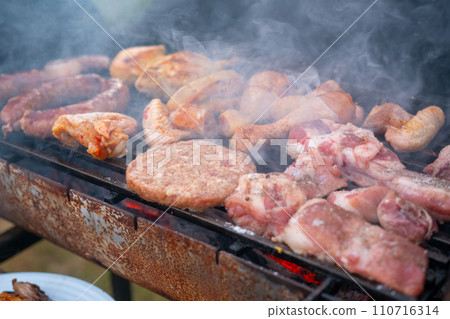 Assorted delicious grilled meat with vegetables over the coals on a barbecue Assorted delicious grilled meat with vegetables over the coals on a barbecue 110716314