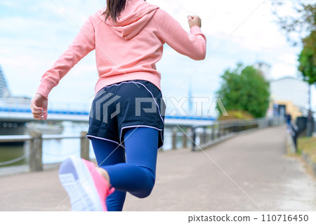 Feet of a young woman jogging outside along the river, diet running wear 110716450