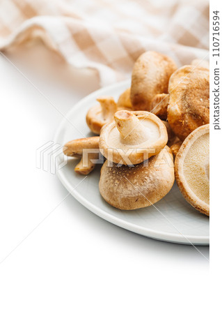 Fresh shiitake mushrooms on plate isolated on white background. Fresh shiitake mushrooms on plate isolated on white background. 110716594