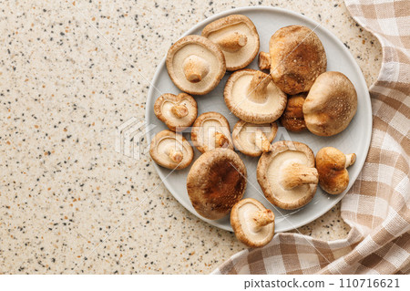 Fresh shiitake mushrooms on plate on kitchen table. Top view. Fresh shiitake mushrooms on plate on kitchen table. Top view. 110716621