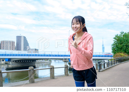 Feet of a young woman jogging outside along the river, diet running wear 110717310