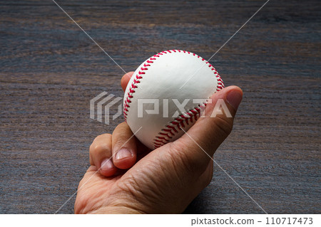 Man's hand holding a hardball baseball ball 110717473