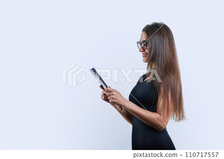 Profile view of a young woman with a folder of papers on a white studio background 110717557