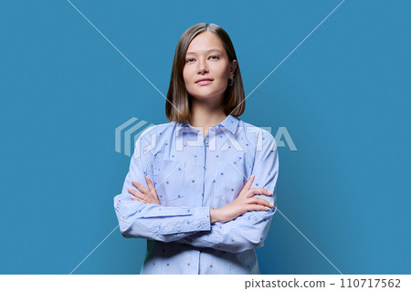 Portrait of confident young woman with crossed arms on blue background Portrait of confident young woman with crossed arms on blue background 110717562