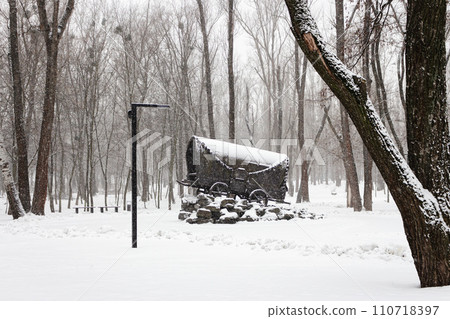 Monument of gypsies holocaust in Babi Yar, Kyiv, Ukraine. Gypsy wagon in snow in memorial of fascism victims. Winter park in blizzard. Kyiv landmark. Historic sightseeing in Ukraine. Monument of gypsies holocaust in Babi Yar, Kyiv, Ukraine. Gypsy wagon in snow in memorial of fascism victims. Winter park in blizzard. Kyiv landmark. Historic sightseeing in Ukraine. 110718397
