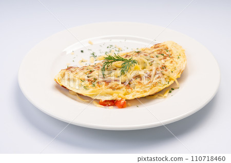 Breakfast. Omelet with vegetables and cheese on a white plate and a white background. 110718460