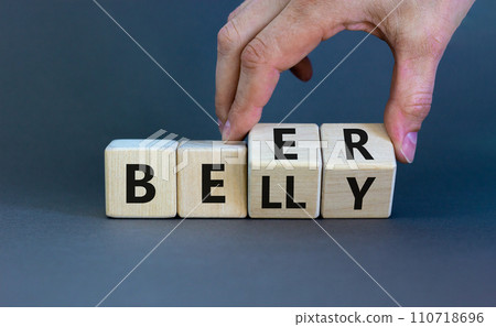 Beer belly symbol. Doctor turns wooden cubes with words 'beer belly'. Beautiful grey table, grey background, copy space. Medical, healthy lifestyle and beer belly concept. 110718696