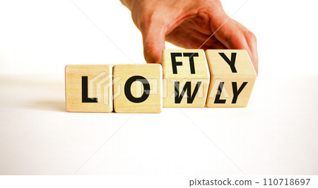 Lofty or lowly symbol. Concept words Lofty Lowly on wooden block. Beautiful white table white background. Businessman hand. Business lofty or lowly concept. Copy space. 110718697