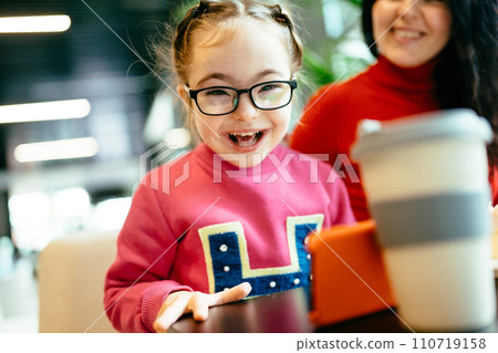 Happy family moments concept. Happy child girl in eyeglasses laughing at camera in cafe indoor. Mother and daughter spend time at coffee shop. 110719158