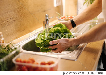 Man washing organic green salad Romano in kitchen. Lettuce leaves with water drops Man washing organic green salad Romano in kitchen. Lettuce leaves with water drops 110720081