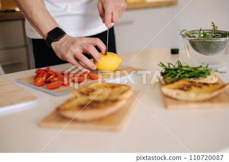 Close-up of male slice fresh lemon on wooden board 110720087
