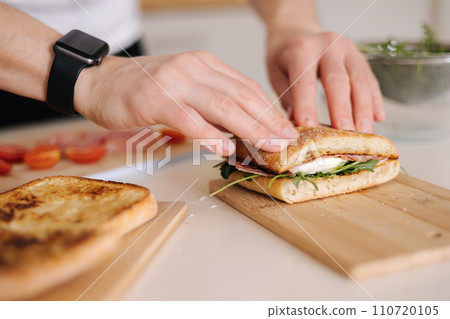 Man presses the top of the sandwich to show juiciness Man presses the top of the sandwich to show juiciness 110720105