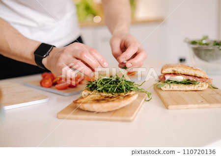 Close-up of man put organic arugula on bruschetta. Vegan food 110720136