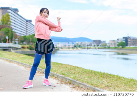 Young woman stretching before jogging along the river, diet, running wear, trimmed up Young woman stretching before jogging along the river, diet, running wear, trimmed up 110720770