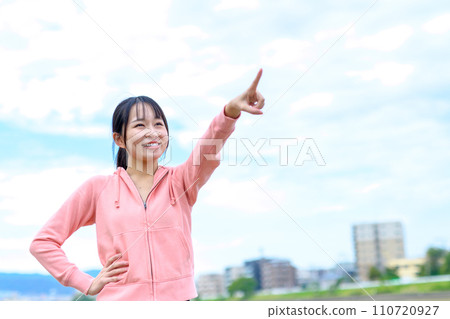 Young woman jogging along the river, pointing, diet, running wear Young woman jogging along the river, pointing, diet, running wear 110720927