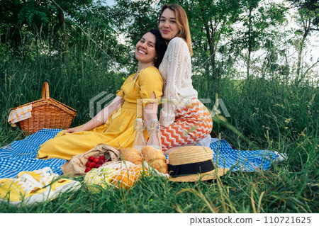 Two young women on a blue blanket outdoors on a picnic Two young women on a blue blanket outdoors on a picnic 110721625