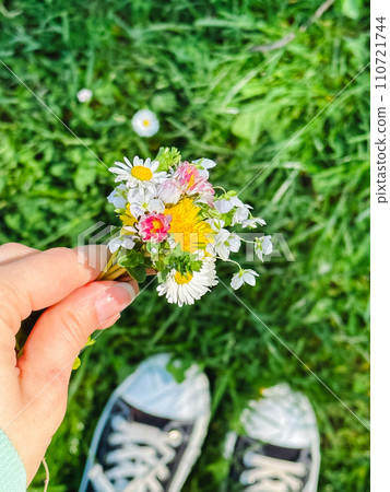 a small bouquet of wildflowers in the hands against the background of the river 110721744