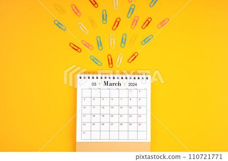March 2024 desk calendar and colorful metal paperclips. March 2024 desk calendar and colorful metal paperclips. 110721771