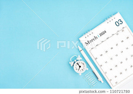 March 2024, Monthly desk calendar for 2024 year and alarm clock with paper clips on blue background. March 2024, Monthly desk calendar for 2024 year and alarm clock with paper clips on blue background. 110721780