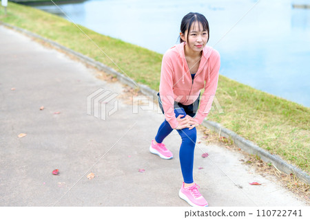年輕女子在河邊慢跑前伸展身體,穿著節食跑步服 年輕女子在河邊慢跑前伸展身體,穿著節食跑步服 110722741