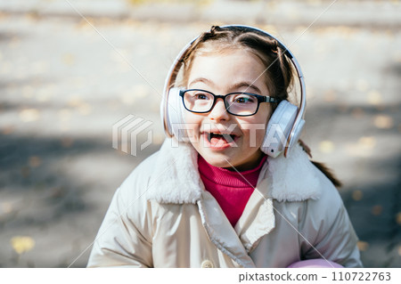 Happy disability kid outdoor portrait. Special need child happy time to use headphones. 110722763