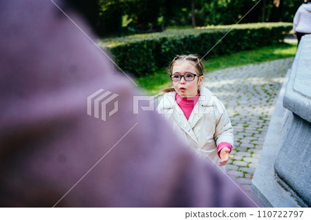 Portrait sad down syndrome girl in eyeglasses standing in front of her mother with a sad face, crying talking. Portrait sad down syndrome girl in eyeglasses standing in front of her mother with a sad face, crying talking. 110722797