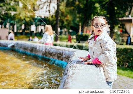 Portrait of beautiful young girl with two braids in eyeglasses, white coat looking aside smiling enjoying good sunny weather in autumn park outdoor. Portrait of beautiful young girl with two braids in eyeglasses, white coat looking aside smiling enjoying good sunny weather in autumn park outdoor. 110722801