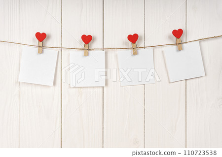 Clothespins with red hearts and empty sheets of paper on string against white wooden background 110723538