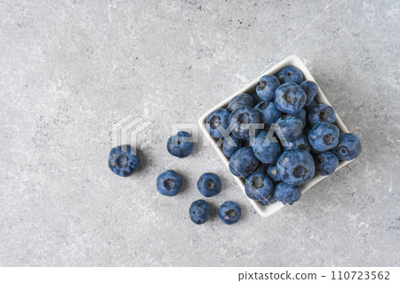Fresh blueberries in a small square bowl on gray concrete background with copy space 110723562