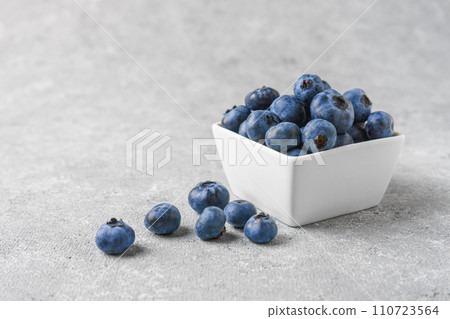 Fresh blueberries in a small square bowl on gray concrete background with copy space Fresh blueberries in a small square bowl on gray concrete background with copy space 110723564