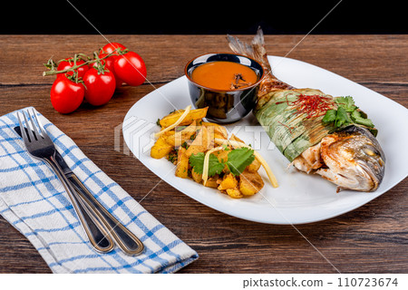 Baked dorado fish in bamboo leaves and Szechuan sauce, potatoes with bamboo shoots. Baked dorado fish in bamboo leaves and Szechuan sauce, potatoes with bamboo shoots. 110723674